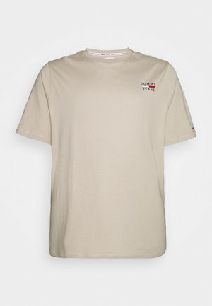 Beżowa koszulka z krótkim rękawem z małym logo "Tommy Jeans" w kolorach czerwonym, białym i czarnym na górnej lewej stronie klatki piersiowej, z okrągłym dekoltem.