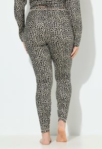 Leggings a stampa leopardata nera e beige con design aderente e materiale elasticizzato, caratterizzati da una consistenza liscia e una lunghezza alla caviglia.