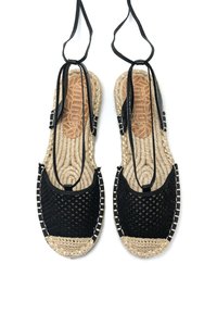 Sandales tissées noires avec un design texturé, dotées de semelles en jute naturel et de brides de cheville réglables pour un maintien sécurisé.