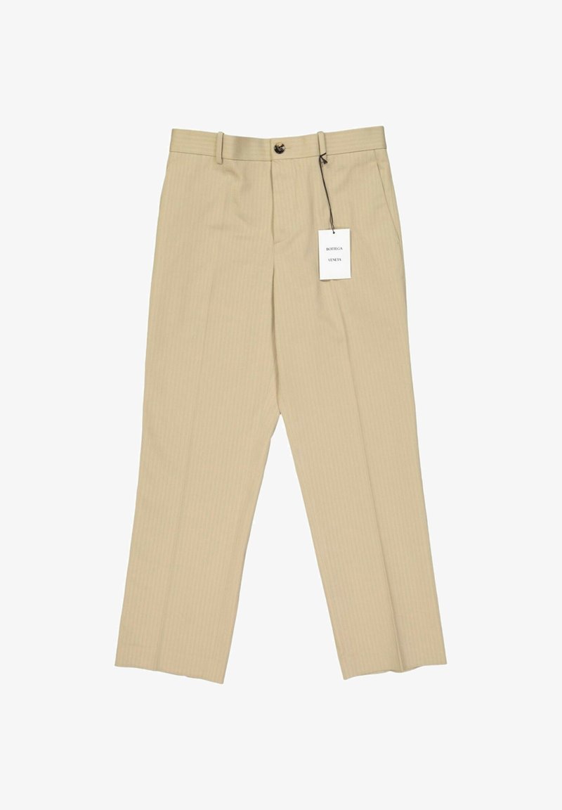 Pantalon beige cintré avec fermeture par bouton et zip, passants de ceinture, poches latérales, et une étiquette blanche Bottega Veneta attachée.