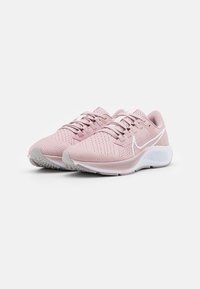 Zapatillas deportivas rosa claro con una parte superior de malla transpirable, cordones a juego, acentos blancos y una suela texturizada gris.