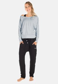 Light blue off-shoulder top with long sleeves, paired with black elastic waist pants featuring pockets and a small embroidered logo.