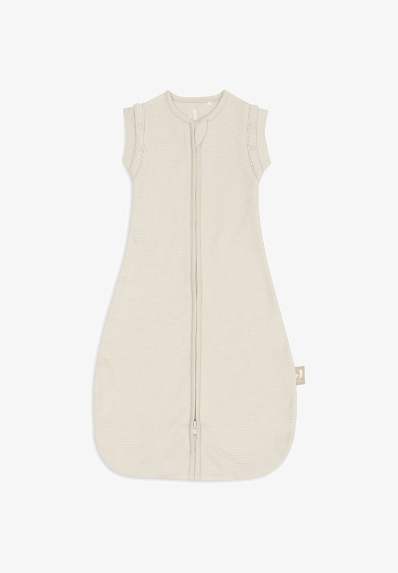 Gigoteuse pour bébé en crème avec design sans manches, fermeture éclair à l'avant et boutons pression aux épaules pour un habillage facile.