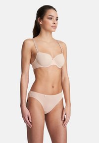 Beiges Wäsche-Set mit einem glatten, gepolsterten BH mit dekorativen Rundträgern und passenden, tief sitzenden Panties, beide aus weichem Stoff.