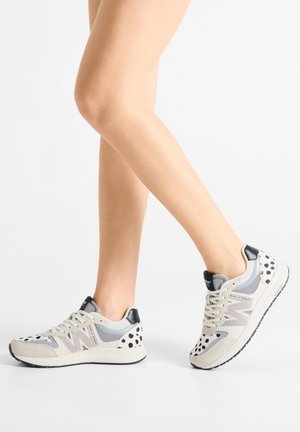 Gray and white sneakers with a mix of mesh and suede. Features black accents and a dotted pattern on the heel. Classic lace-up design.