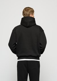 Schwarzer Hoodie mit einer großen, strukturierten Kapuze und herunterhängenden Schultern. Der Stoff wirkt weich, verfügt über einen gerippten Taillenausschnitt und hat eine dezente Textur.