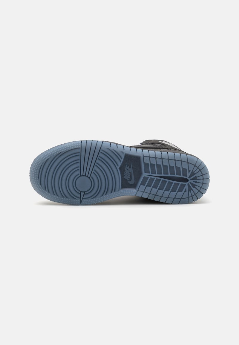 Baskets noires avec une surface texturée, dotées d'une semelle extérieure en caoutchouc bleue avec des motifs de bande de roulement circulaires et linéaires, ainsi qu'un logo proéminent.