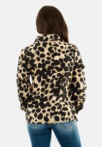 Camicia con stampa leopardo in beige e nero, dotata di colletto e maniche lunghe, realizzata in un tessuto morbido.