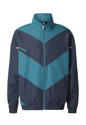 Løpejakke i blågrønn og marineblå med høy krage, full glidelås og chevronmønster. Laget av glatt stoff med elastiske mansjetter og kant.