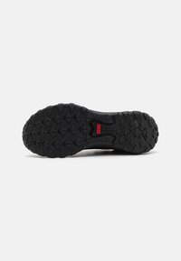 Semelle de chaussure noire robuste avec des crampons profonds et une étiquette rouge "MTE" au centre, conçue pour la traction en extérieur.