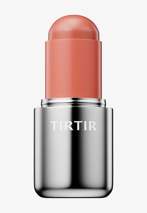 Stick de blush crème couleur corail de la marque Tirtir avec un boîtier argenté brillant sur fond blanc.