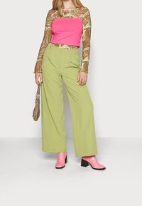 Růžový upnutý top vrstvený pod dlouhým rukávem, blůzou s mramorovým vzorem. Široké světle zelené kalhoty. Růžové lesklé boty na podpatku.