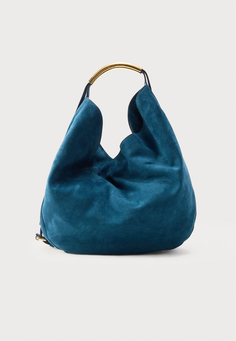 Sac hobo en daim bleu avec une forme souple et décontractée et une anse incurvée en métal doré sur un fond clair uni.