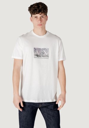T-shirt bianca in cotone con maniche corte, caratterizzata da una stampa grafica rettangolare con il logo "AX" e "ARMANI EXCHANGE" in tonalità più scure.