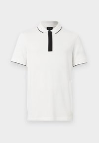 Camiseta polo blanca de manga corta con ribete negro en el cuello y las mangas, tapeta negra y logo de Armani Exchange en la etiqueta interior del cuello.