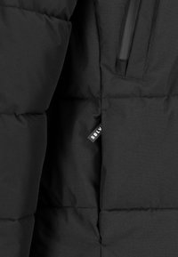 Black puffer jacket interior, featuring quilted design, smooth texture, zippered pocket, and a tag displaying "SBLV" near the hem.