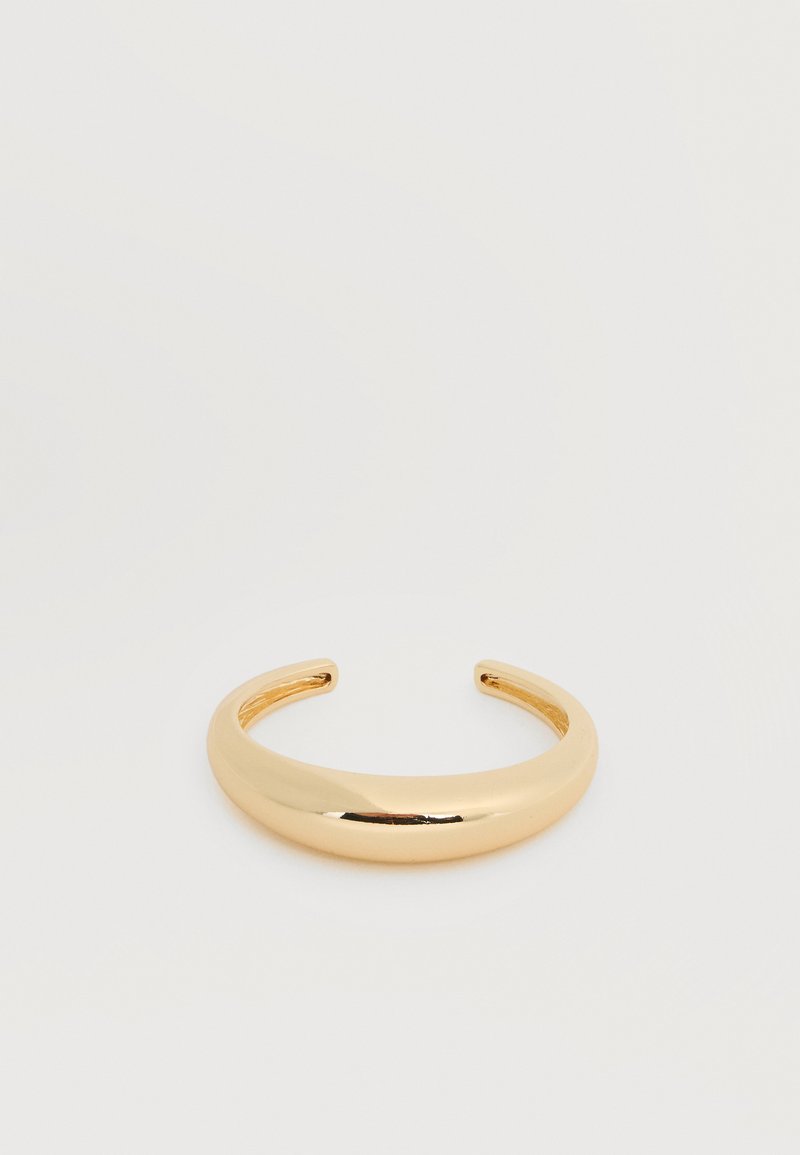 Λείος, λαμπερός χρυσός βραχιόλι μανσέτα με ελαφρώς κυρτό, ανοιχτό σχέδιο σε απλό λευκό φόντο.