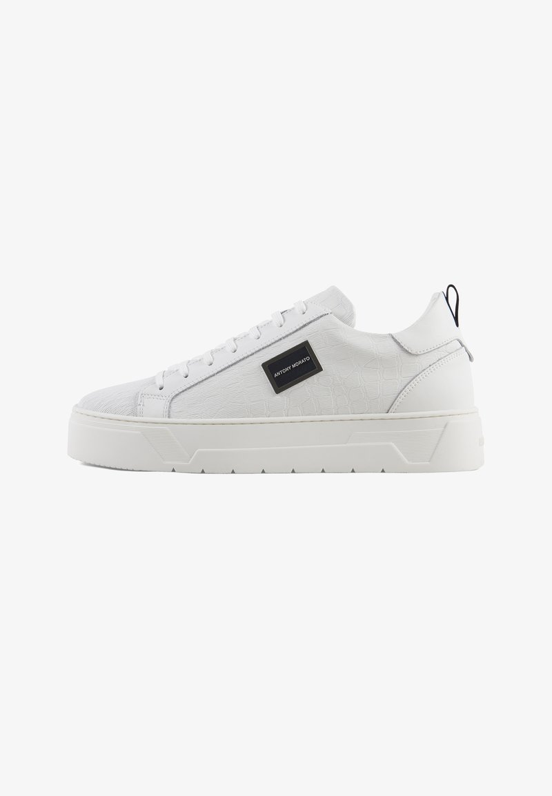 Sneakers bianchi con pattern a rilievo in croco, tomaia sintetica liscia, suola piatta e un logo nero accento sul lato.
