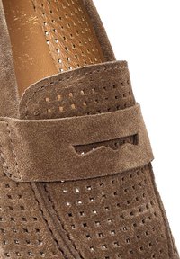 Mocassins en suede marron avec design perforé, présentant un dessus texturé, une sangle plate avec des découpes, et une doublure en cuir lisse.