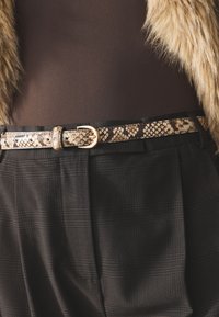 Black plaid high-waisted trousers with a smooth brown bodysuit. Features a beige snake-print belt with a gold buckle for accent.