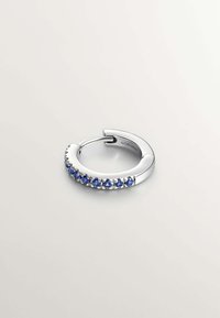 Pendiente de aro de plata con una fila de piedras preciosas azules en la parte delantera. Acabado suave con una textura brillante y diseño de cierre seguro.