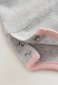 Grå ribbad tyg med rosa detaljer, prytt med metallknappar. Materialet har en mjuk textur med en lätt stretch.