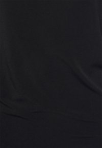 Tecido preto com textura suave e ligeiro brilho, exibindo pregas sutis e variações de cor em toda a superfície.