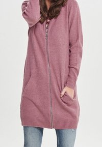 Langer, Reißverschluss-Cardigan aus weichem, rosa Strickstoff. Mit gerippten Bündchen und Saum, sowie zwei Vordertaschen für Funktionalität.