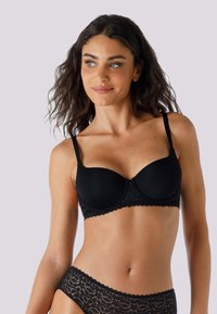 Bra nero realizzato in tessuto liscio con un bordo in pizzo. Il design presenta coppe imbottite e spalline regolabili.