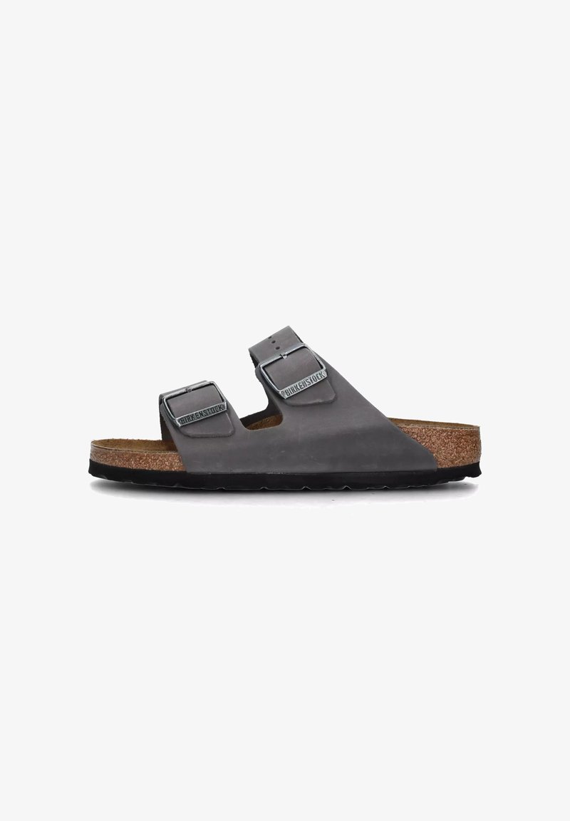 Sandal grigio a due cinghie con fibbie regolabili, plantare in sughero e suola in gomma nera, caratterizzato da un materiale superiore liscio e un design minimale.