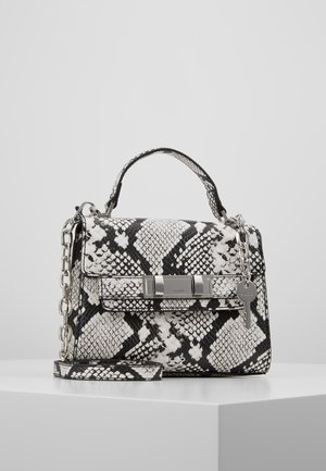 Sac à main à motif peau de serpent en noir et blanc avec anse supérieure, chaîne argentée, fermoir avant et pendentif clé suspendu sur une surface blanche.