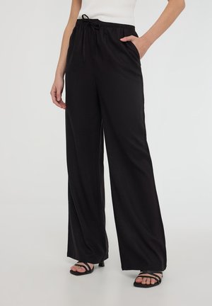 Pantaloni neri a gamba larga realizzati in tessuto leggero, con una vita elasticizzata dotata di cordino, tasche laterali e una texture liscia.