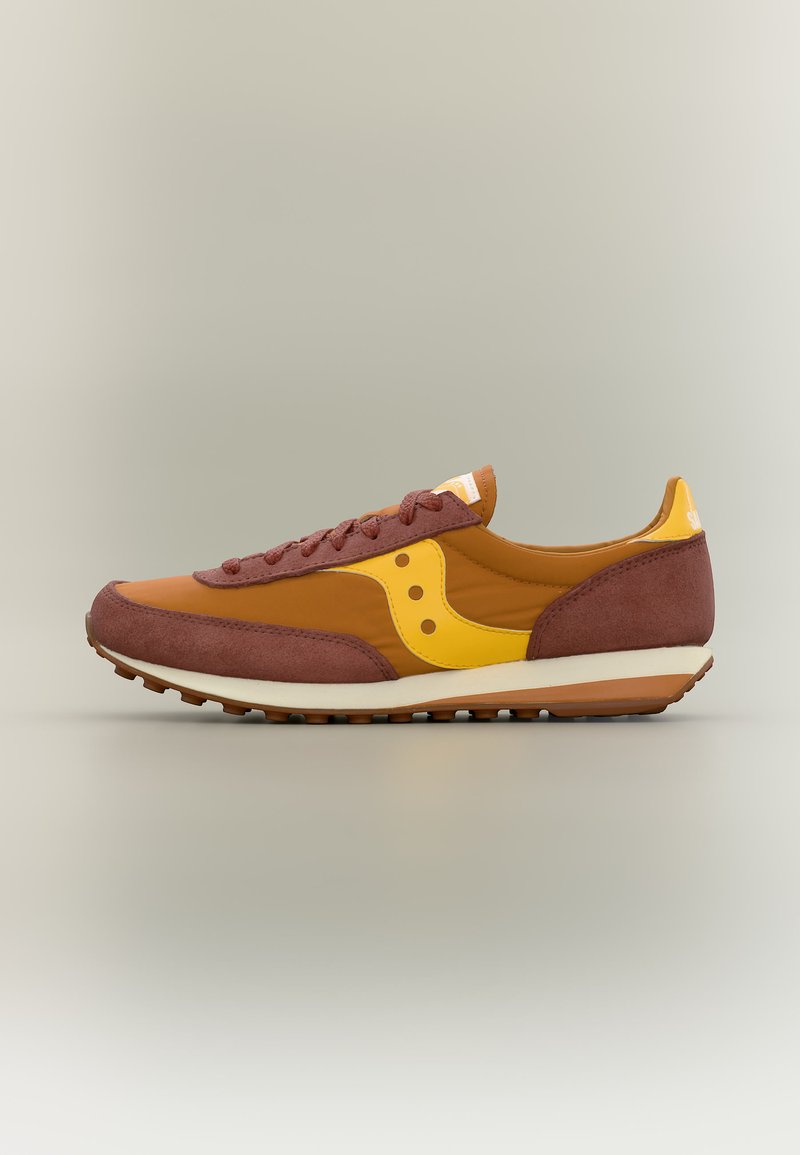 Chaussure de course profilée en marron et jaune avec accents en daim, fermeture à lacets, semelle en caoutchouc et logo de marque sur le côté.