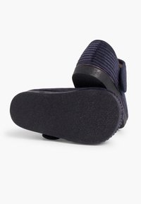 Navy modré nazouvací boty s texturovaným svrchním materiálem, gumovou podrážkou a zakřivenou patou. Obsahují pásek s hook-and-loop pro bezpečné upevnění.