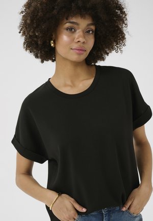 Black, short-sleeve t-shirt with rolled cuffs, soft texture, round neckline, worn casually with blue jeans and gold bangle on wrist.