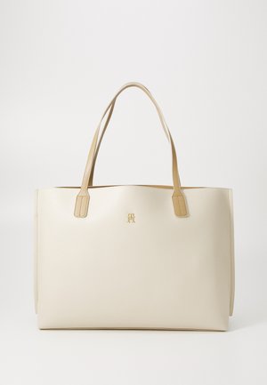 Tote bag made of cream-colored textured leather with contrasting tan handles and a gold logo accent. Rectangular shape, minimalist design.