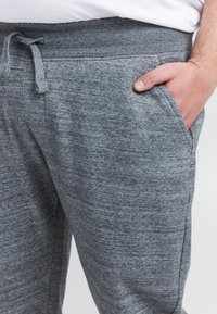 Grijze joggingbroek gemaakt van een zachte, gestructureerde stof. Voorzien van een elastische tailleband met trekkoord en zijzakken.