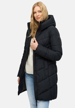 Sort puff jakke med hætte, der har et quiltet design, lynlås lukning og sidelommer. Båret over en let sweater og jeans.