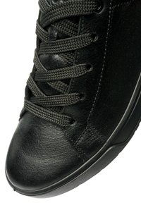 Black leather sneaker with textured surface, flat black laces, and a rubber sole. Features subtle stitching and a rounded toe design.