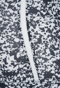 Svart och vit mönstrad tyg med en texturerad meshpanel. Har synliga sömdetaljer längs sömmen för hållbarhet och design.