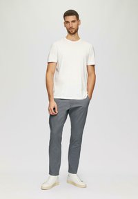 Witte crewneck t-shirt, slim-fit grijze broek en witte sneakers. Gladde stof, casual ontwerp en een minimalistische look zonder patronen.