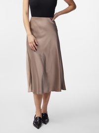 Midi-lange, beige satijnen rok met een gladde textuur, uitlopende stijl en een rechte zoom, gecombineerd met zwarte schoenen met een puntige neus.
