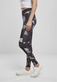 Höga leggings med ett svart blommönster och genomskinliga meshutsnitt. Tillverkade av stretchtyg, med en slät textur och en figurnära design.
