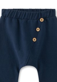 Marineblaue Baumwollhose mit elastischem Bündchen, ausgestattet mit drei dekorativen Holzknöpfen auf der linken Seite und einer glatten Textur.