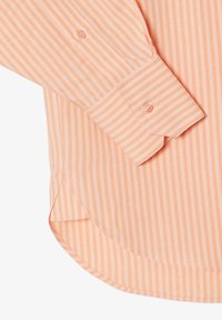 Puño de camisa de manga larga con botón, con rayas verticales en color durazno y blanco y un dobladillo redondeado sobre un fondo blanco.