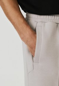 Gray sweatpants made of soft material with an elastic waistband, featuring side pockets and a subtle textured finish.
