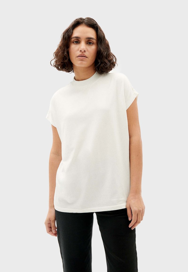 Witte, korteg mouw t-shirt met een ronde hals, gestructureerde pasvorm en zachte textuur. Gedragen met zwarte broek, wat een casual stijl laat zien.