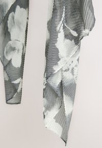 Kevyt, kuvioitu huivi harmaan ja valkoisen monokromaattisissa sävyissä, jossa on kukkakuvio ja raidallinen rakenne sekä terävät päät.