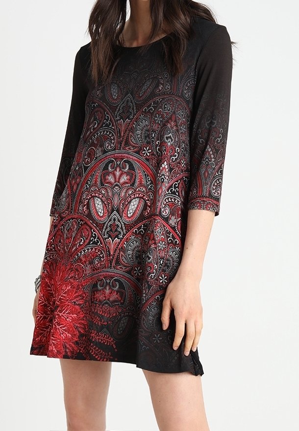Czarna sukienka z czerwono-srebrnym ozdobnym nadrukiem w motyw paisley. Posiada rękawy do połowy przedramienia i luźny krój, z lekko rozszerzanym dołem.