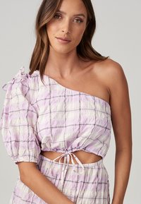 Top leggero, off-the-shoulder in un delicato motivo a quadri viola pastello. Presenta maniche a palloncino e un elastico in vita per una vestibilità regolabile. Tessuto morbido.